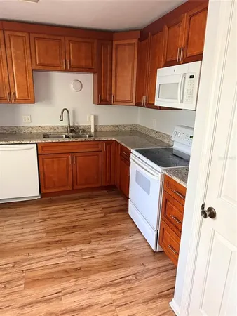 a kitchen with granite countertop a refrigerator and a stove top oven