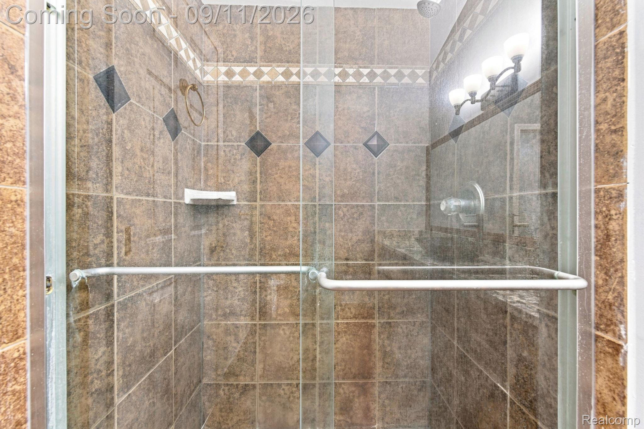 3201 Lynhurst Court Rochester, MI 48306 - Photo 21 of 43 Tiled shower with glass enclosure, decorative accent tile, and wall-mounted showerhead