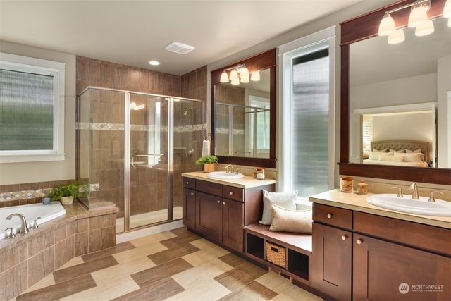 a bathroom with a granite countertop tub double vanity sink a mirror and a shower