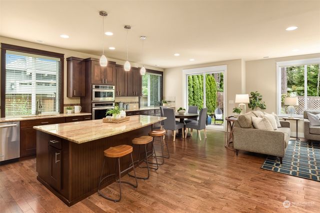 a open kitchen with stainless steel appliances granite countertop a table chairs and a large window