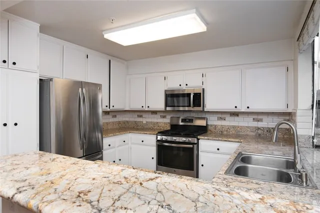 a kitchen with stainless steel appliances granite countertop a stove a sink and a microwave