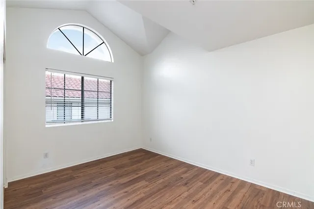 an empty room with wooden floor cabinet and a window