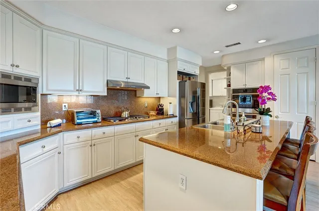 a kitchen with kitchen island granite countertop a sink cabinets and stainless steel appliances