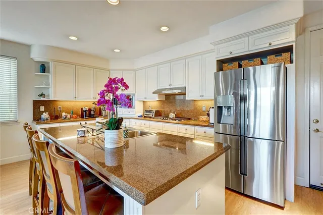 a kitchen with stainless steel appliances granite countertop a sink refrigerator and cabinets