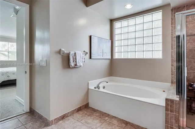 a white bath tub sitting in a en suite bathroom next to a window