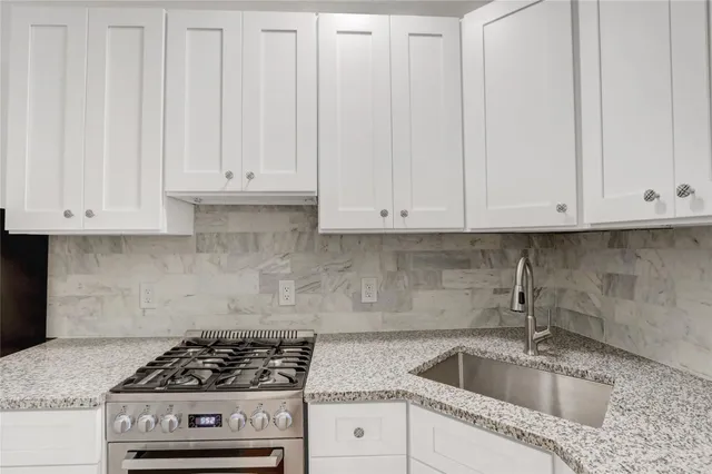 a kitchen with granite countertop white cabinets and stainless steel appliances