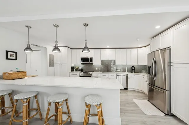 a kitchen with stainless steel appliances kitchen island granite countertop a table chairs and a refrigerator