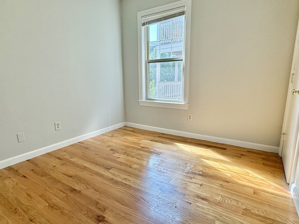 184 Boston Street, Unit 2 Boston, MA 02125 - Photo 11 of 14 an empty room with wooden floor and windows