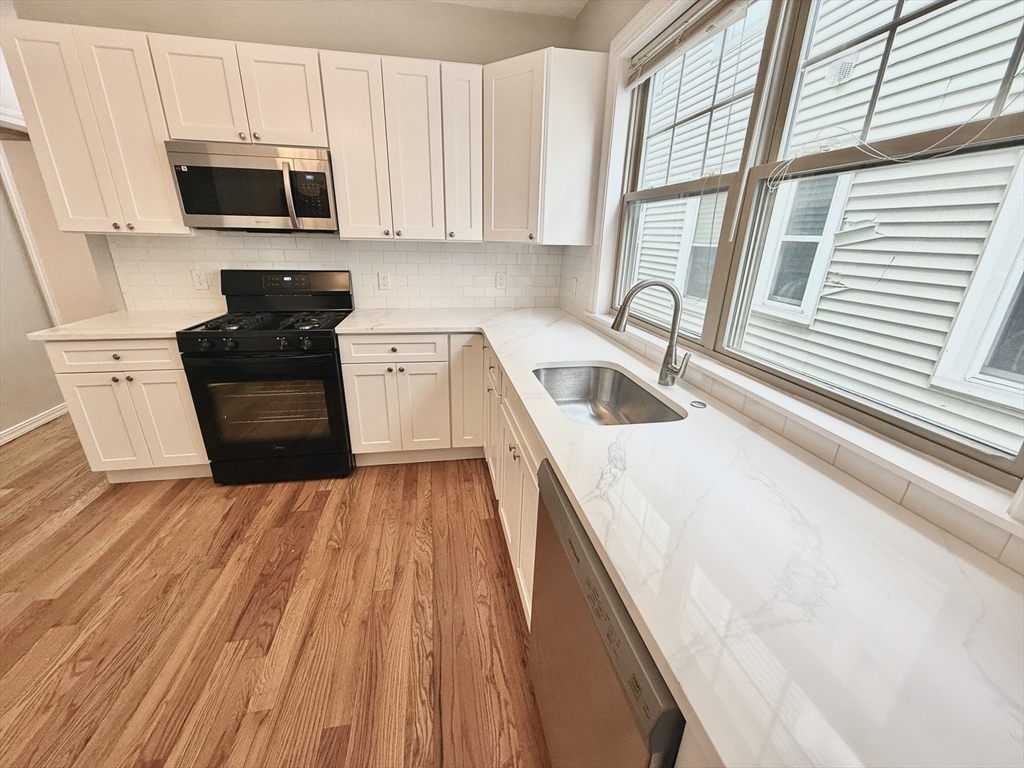 184 Boston Street, Unit 2 Boston, MA 02125 - Photo 3 of 14 a kitchen with granite countertop a sink a stove top oven and cabinetry