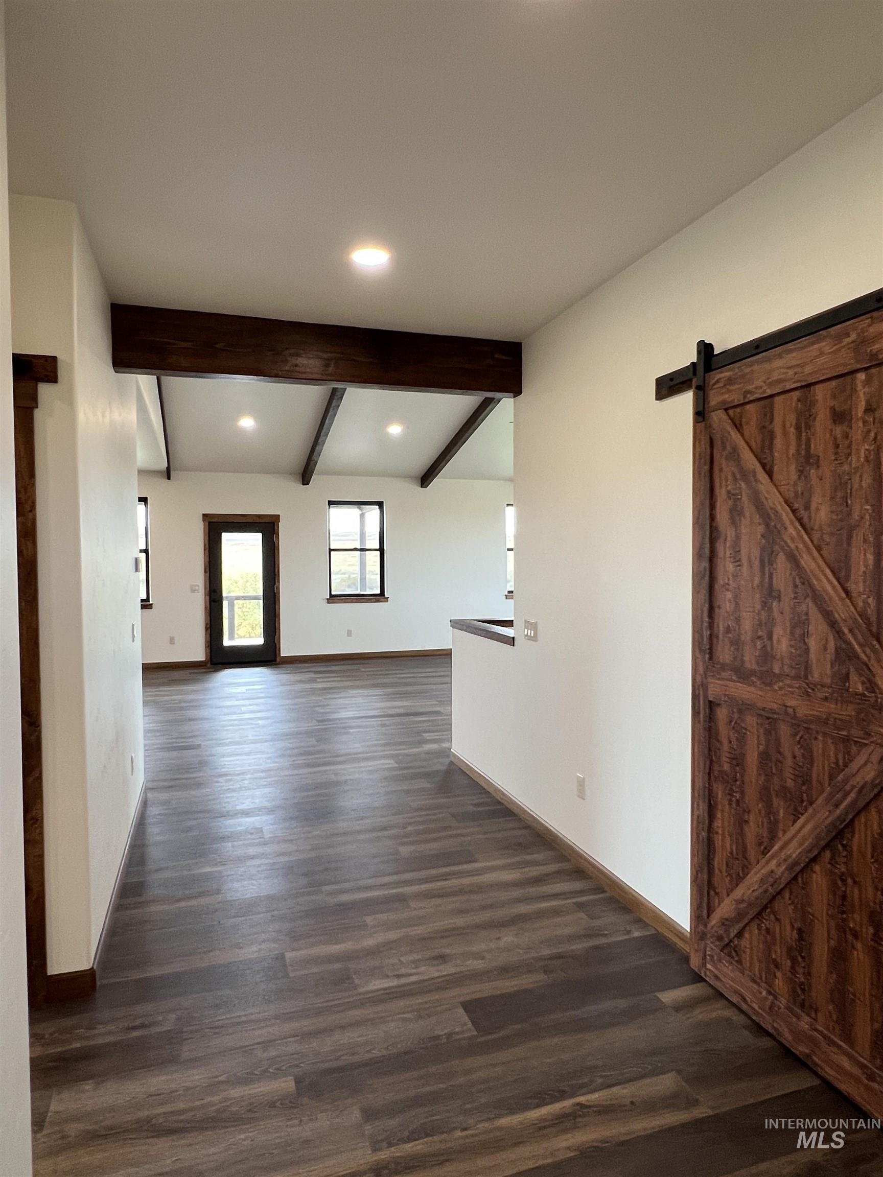 137 Angus Ranch Grangeville, ID 83530 - Photo 6 of 49 Unfurnished room featuring a barn door, beamed ceiling, dark wood-style flooring, and recessed lighting