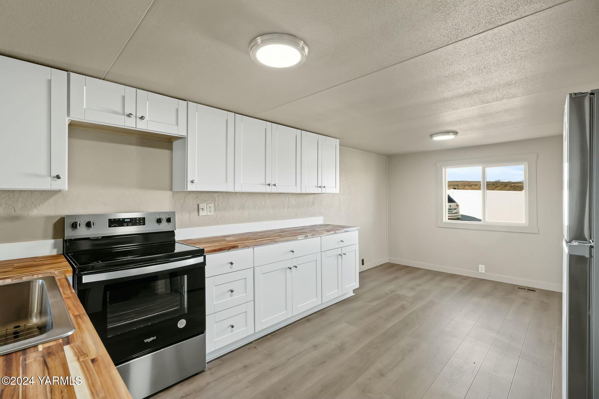 590 Hideaway Road Yakima, WA 98908 - Photo 11 of 34 a kitchen with granite countertop white cabinets and stainless steel appliances