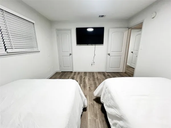 a bedroom with a bed a flat screen tv and a window