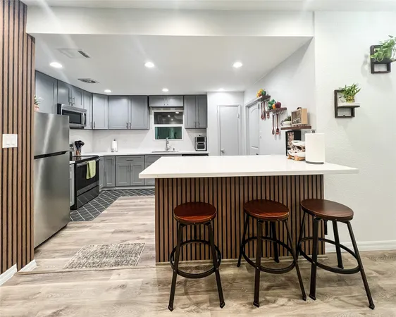 a kitchen with stainless steel appliances kitchen island granite countertop a table chairs and a refrigerator