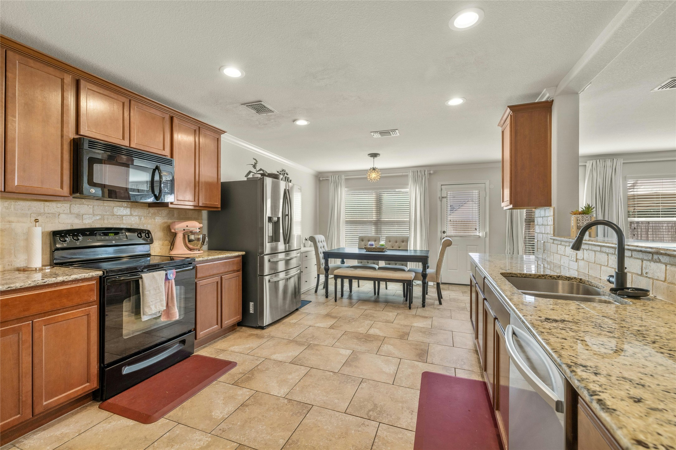 104 Bufflehead Lane Leander, TX 78641 - Photo 11 of 34 Kitchen with backsplash, black appliances, light stone countertops, brown cabinetry, and recessed lighting