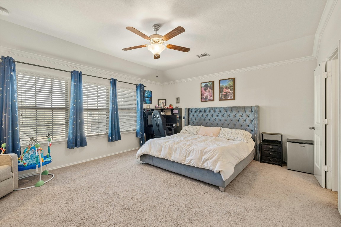 104 Bufflehead Lane Leander, TX 78641 - Photo 16 of 34 a spacious bedroom with a large bed and a chandelier