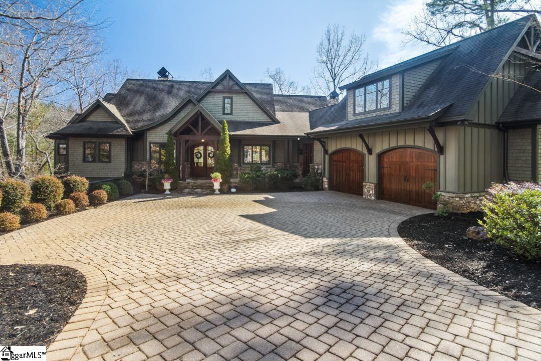 A welcoming Craftsman-style home with timber accents, stone details, and a sweeping paver driveway that sets a refined, private tone from the moment you arrive.