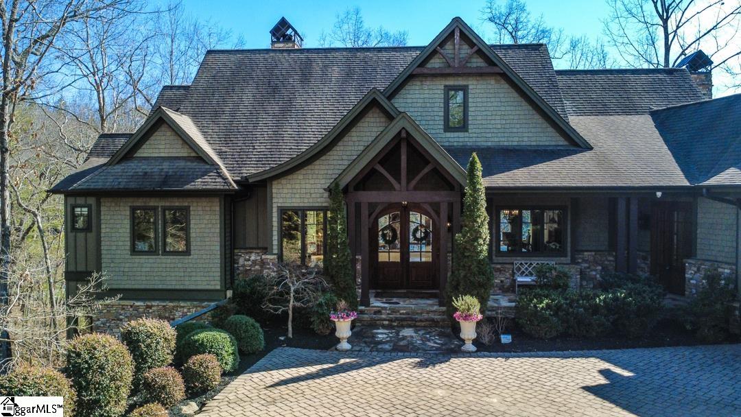 206 Feather Bell Lane Sunset, SC 29685 - Photo 2 of 50 An inviting timber-framed entry with arched wood doors, stone accents, and curated landscaping creates an immediate sense of warmth.