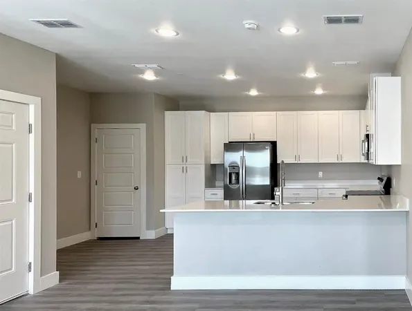 a large kitchen with stainless steel appliances granite countertop a large counter top a sink and a refrigerator