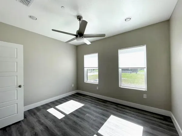 a view of empty room with wooden floor and fan
