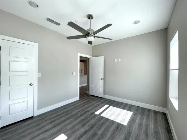 an empty room with wooden floor and windows