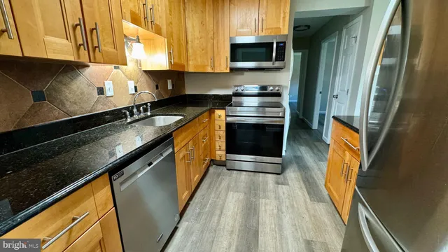 a kitchen with stainless steel appliances granite countertop a stove a sink and a microwave