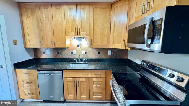 a kitchen with granite countertop a stove a sink and a microwave