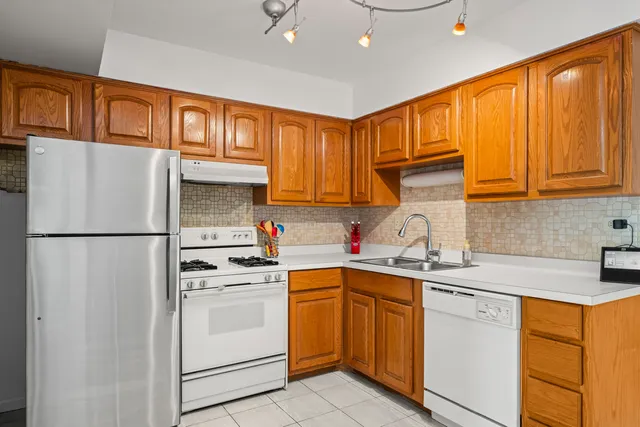a kitchen with a sink cabinets stainless steel appliances and a refrigerator