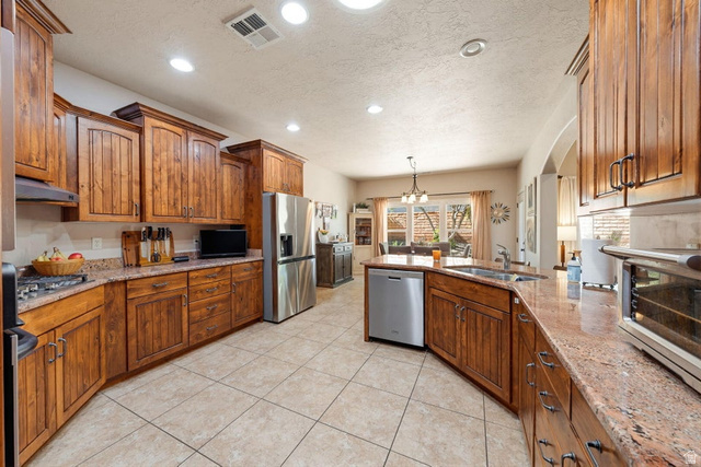 1609 East 10 S Street St. George, UT 84790 - Photo 21 of 68 Open-concept kitchen featuring extensive wood cabinetry, granite countertops, stainless steel appliances, a built-in kitchen sink, and tile flooring