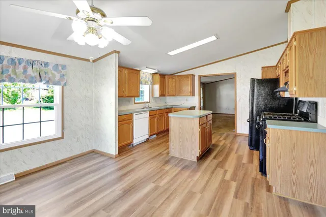 a kitchen with stainless steel appliances granite countertop a refrigerator a stove top oven a sink dishwasher and white cabinets with wooden floor