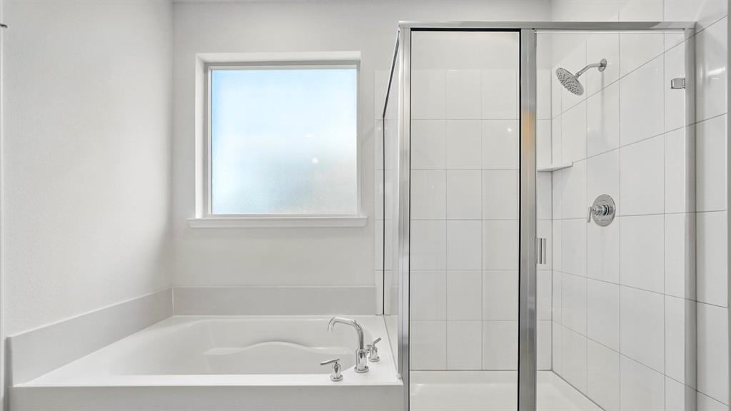4191 Waldron Trail Forney, TX 75126 - Photo 12 of 20 Bathroom featuring a built-in tub with chrome fixtures, a frosted window, and a glass-enclosed shower with white subway tile surround and a rainfall showerhead