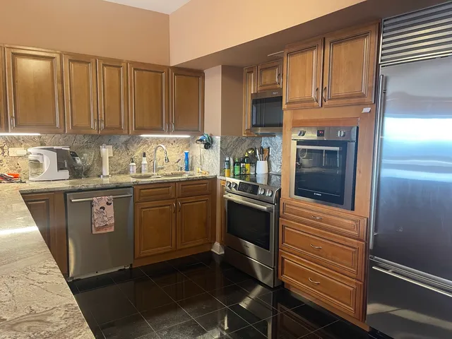 a kitchen with stainless steel appliances granite countertop a sink a stove and refrigerator