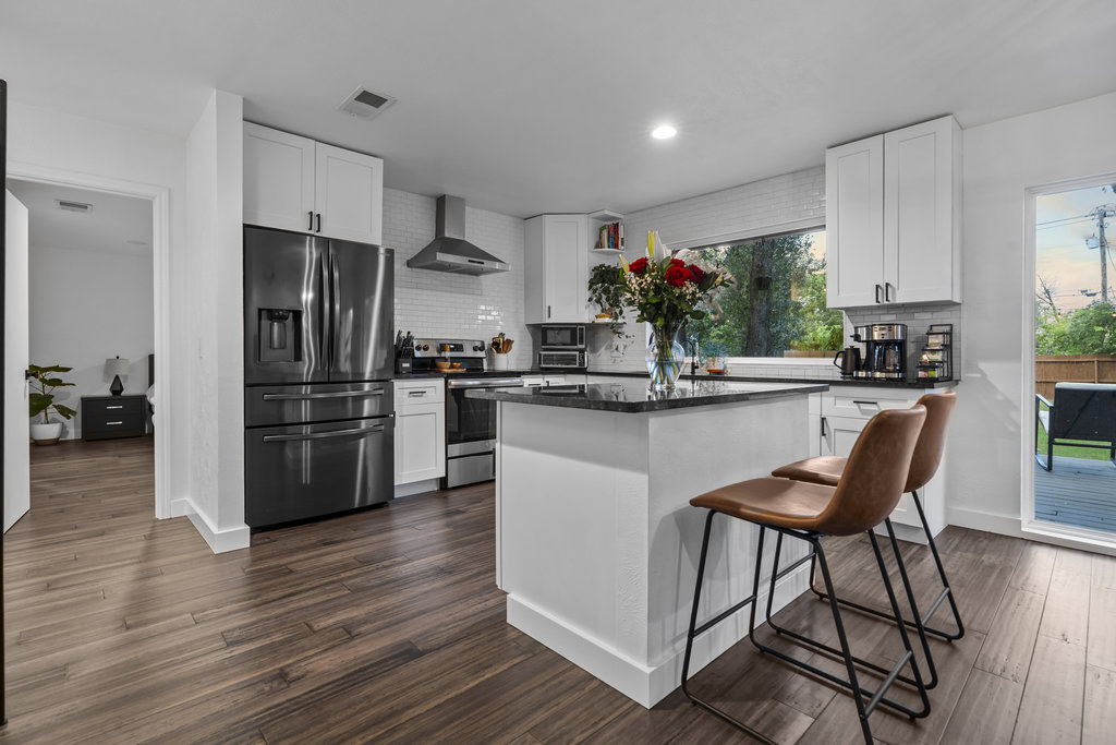 9308 Meadowheath Drive Austin, TX 78729 - Photo 14 of 40 a kitchen with stainless steel appliances kitchen island granite countertop a table chairs stove and refrigerator