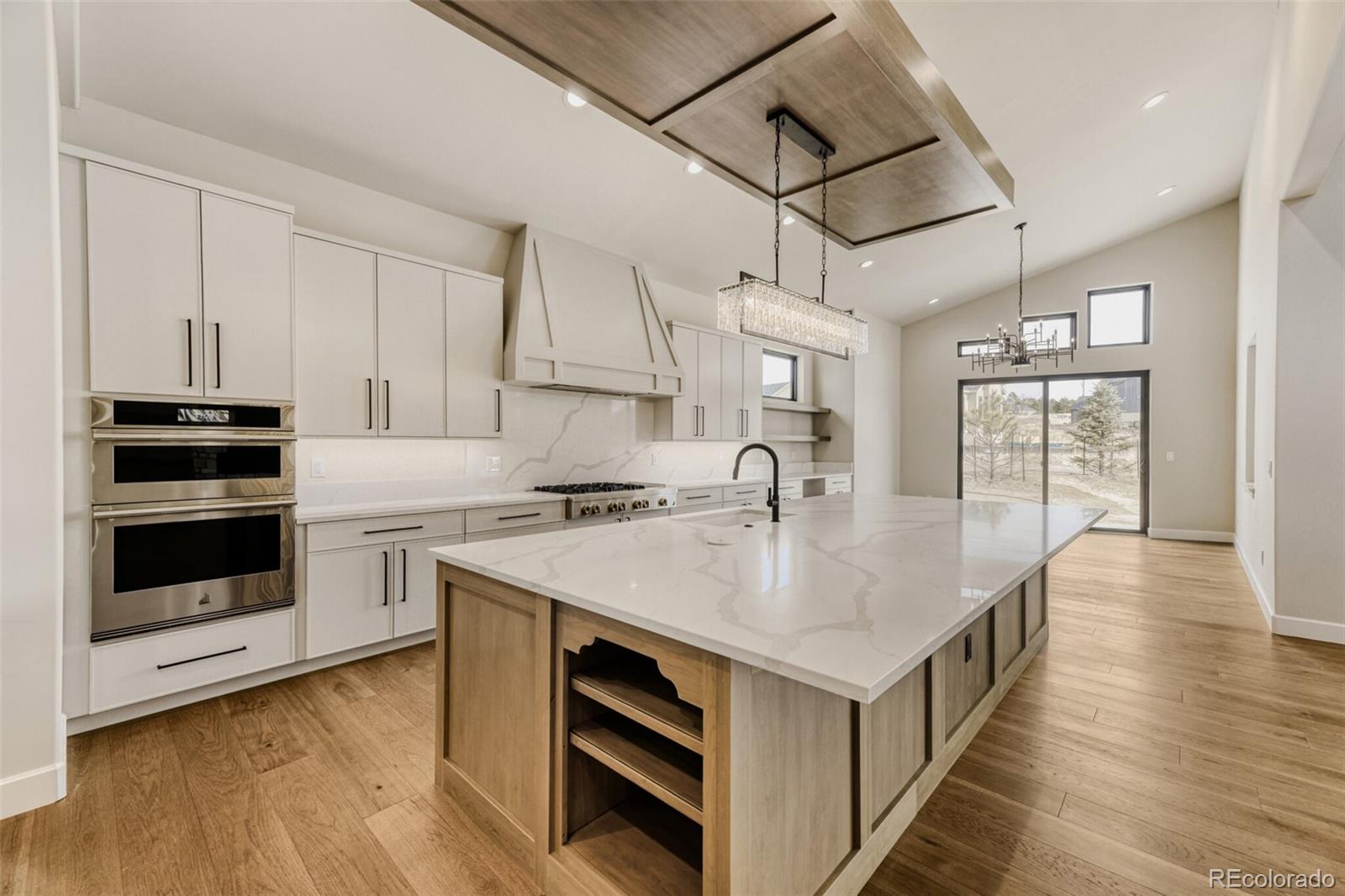 5796 Powell Road Parker, CO 80134 - Photo 12 of 50 a kitchen with kitchen island a stove a sink and white cabinets with wooden floor