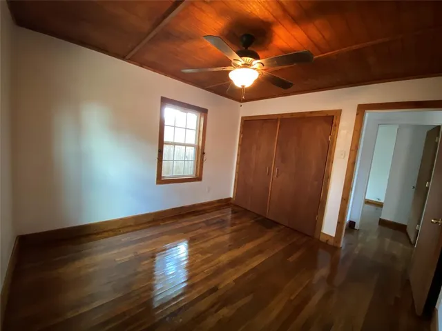 a view of an empty room with wooden floor and a fan