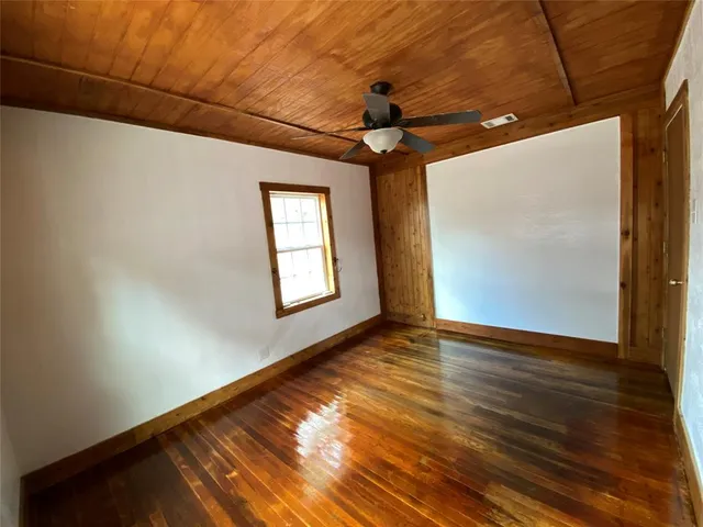 a view of an empty room with window and wooden floor