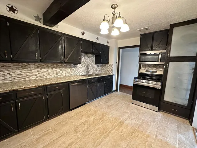 a kitchen with granite countertop stainless steel appliances a stove refrigerator and cabinets