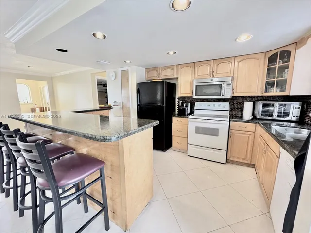 a kitchen with stainless steel appliances kitchen island granite countertop a table chairs and a refrigerator