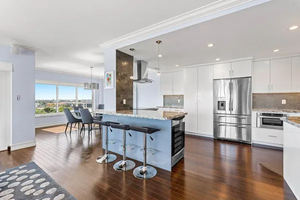 a kitchen with stainless steel appliances granite countertop a stove refrigerator and a dining table with wooden floor