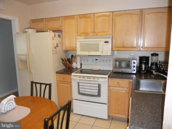 10506 Royal Road Silver Spring, MD 20903 - Photo 6 of 11 a kitchen with stainless steel appliances granite countertop a refrigerator a stove a sink a dining table and chairs with wooden floor