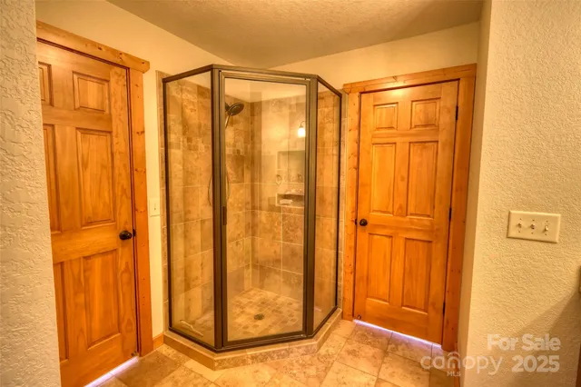 a bathroom with a glass door shower and closet