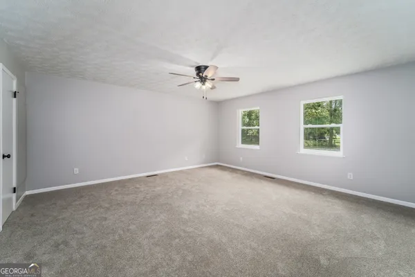 an empty room with windows and ceiling fan