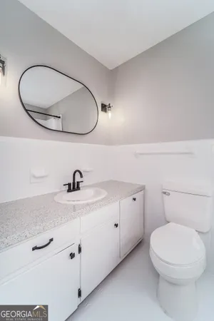 a bathroom with a granite countertop toilet sink and mirror