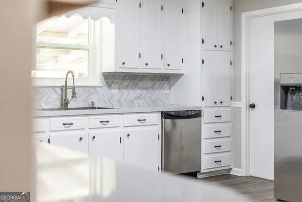 a kitchen with granite countertop white cabinets and a sink