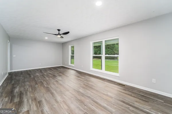 a view of an empty room with a window and wooden floor