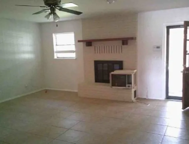an empty room with windows and fireplace