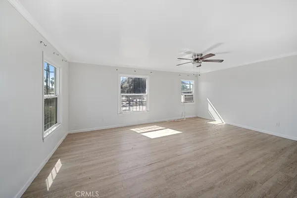 a view of empty room with wooden floor and fan