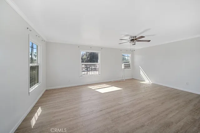 a view of empty room with wooden floor and fan