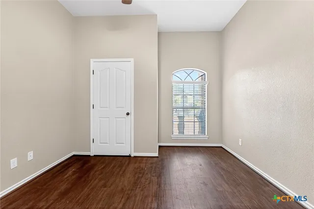 an empty room with wooden floor ceiling fan and carpet