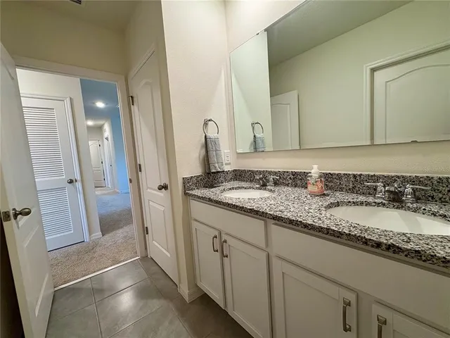 a en suite bathroom with a granite countertop sink and a mirror