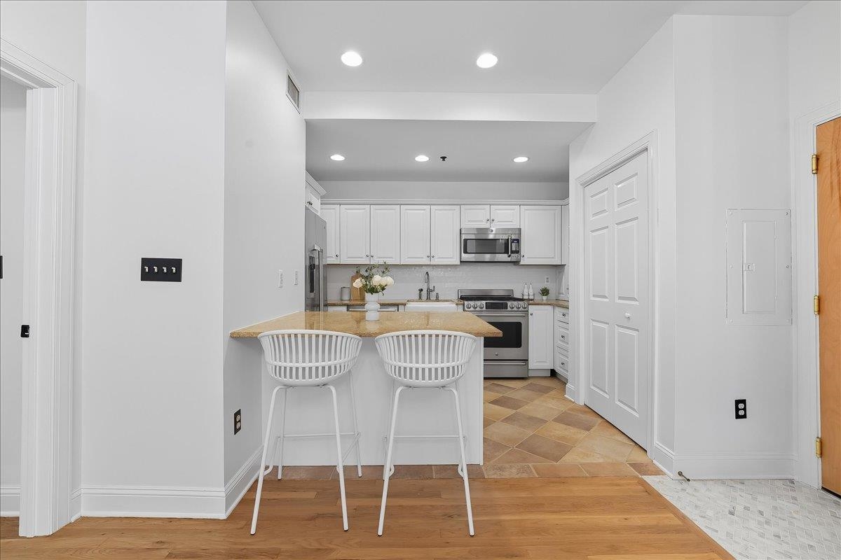 829 Washington Street, Unit 8 Hoboken, NJ 07030 - Photo 20 of 36 a kitchen with kitchen island granite countertop a dining table chairs cabinets and stainless steel appliances